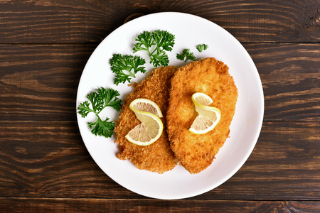 Chicken schnitzel on plate over wooden background. Top view, flat layの写真素材