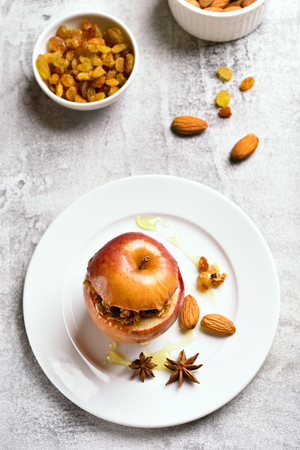 Appetizing baked apple with granola, cinnamon, nuts and honey on stone background. Healthy fruit dessert. Top view
の写真素材