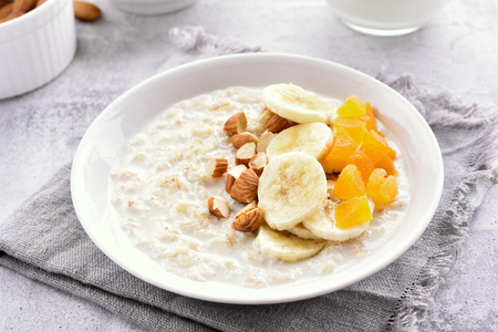 Tasty oats porridge with banana slices, nuts and dried apricot. Natural healthy food. Diet breakfast. Close up viewの写真素材