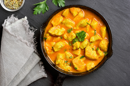 Chicken curry in frying pan on dark stone background. Top view, flat lay. の写真素材