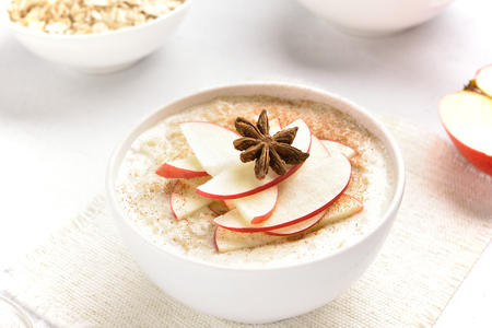 Bowl of oats porridge with red apple slices and cinnamon. Healthy diet breakfast concept. Close up view
の写真素材