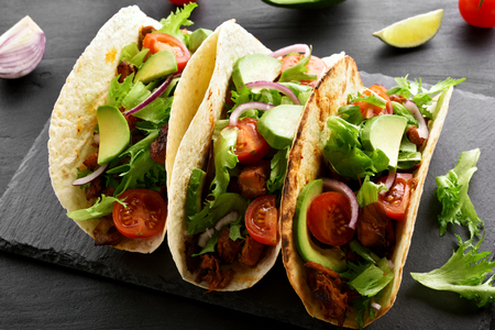 Tortilla, tacos with meat and vegetables on black stone boardの写真素材