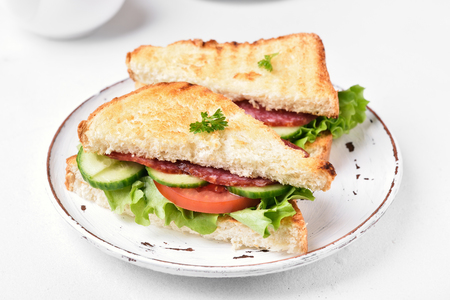 Close up of club sandwiches with salami, tomatoes, cucumber and lettuceの写真素材