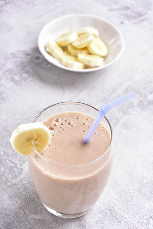 Healthy beverage. Banana smoothie in glass on stone background. の写真素材