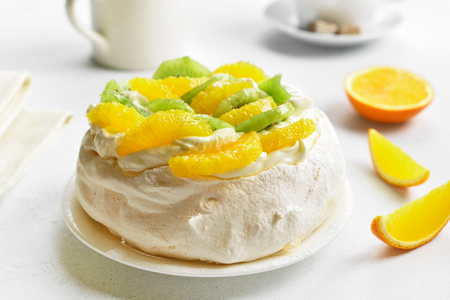 Dessert pavlova meringue cake with kiwi, orange slices and whipped cream. の写真素材