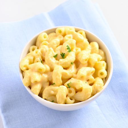 Close up of macaroni and cheese with herbs  in white bowlの写真素材