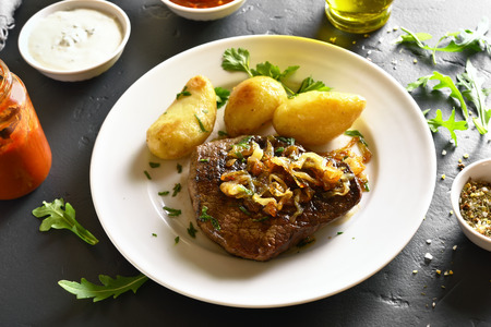 Medium rare roast beef with potato on black stone tableの写真素材