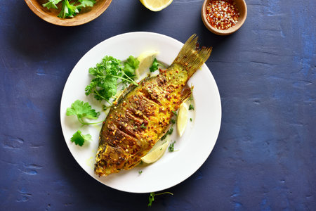 Roasted fish on plate over blue stone background with copy space. Top view, flat lay