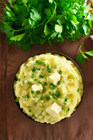 Mashed potatoes with green onion and butter in bowl. Top view, flat layの写真素材