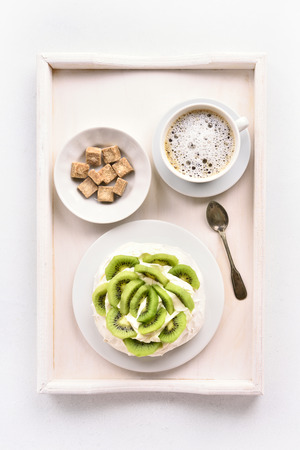 Pavlova meringue cake with kiwi slices and cup of coffee. Top view, flat layの写真素材