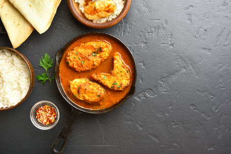 Fish curry in frying pan on black stone background with copy space. Indian style food. Top view, flat layの写真素材