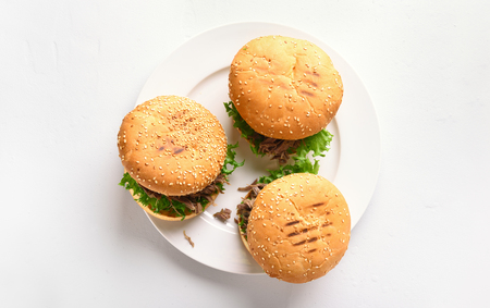 Pulled beef hamburgers with vegetables on plate over white stone background. Top view, flat layの写真素材
