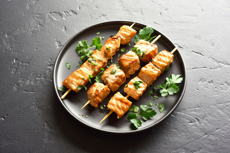 Grilled salmon kebab. Barbecue salmon skewers on black stone background.の写真素材