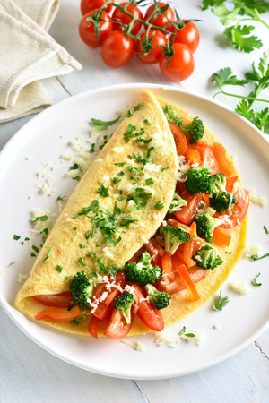 Omelet with tomatoes, red bell pepper and broccoli on light wooden table. Healthy diet food for breakfast. Tasty morning food.の写真素材