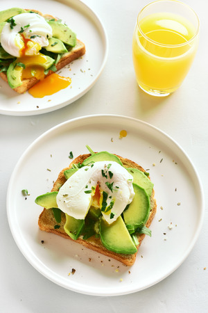Breakfast with poached eggs on toasted bread and orange juice. Healthy morning food. Top view, flat layの写真素材