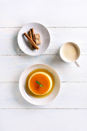 Caramel custard pudding on plate and cup of coffee over wooden table. Top view, flat layの写真素材