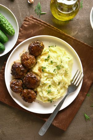 Minced meat cutlets with mashed potatoes on white plate over brown background. Top view, flat layの写真素材