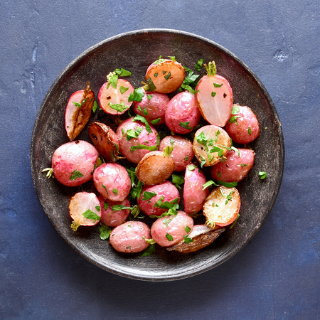 Close up of roasted radish on plate over blue stone background. Top view, flat layの写真素材