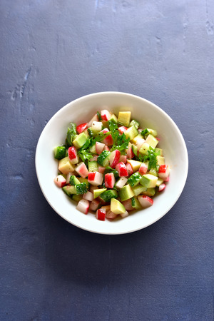 Healthy vegetable salad from avocado, radish, cucumber, greens in bowl over blue stone background. Organic natural or vegetarian vegan food concept.の写真素材