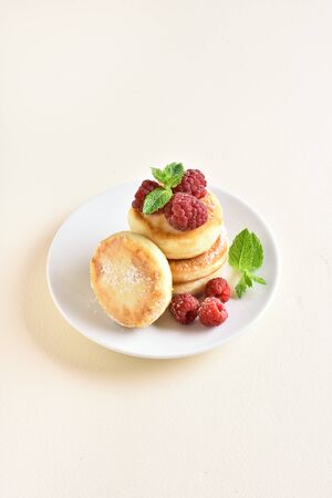 Cottage cheese pancakes with fresh raspberries on plate over light stone background with free space for text.の写真素材