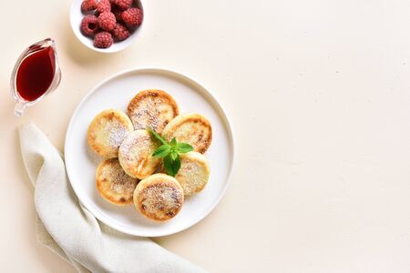 Cottage cheese pancakes with fresh raspberries on plate over light stone background with free space. Top view, flat layの写真素材