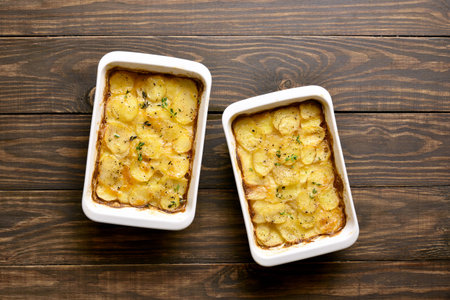 Potato gratin in baking dish over wooden background. Top view, flat lay