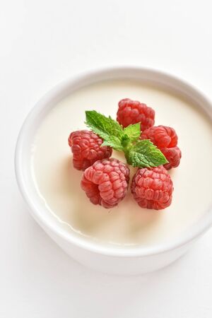 Close up of panna cotta with fresh raspberries in bowl on white stone background. Delicious dessert.の写真素材