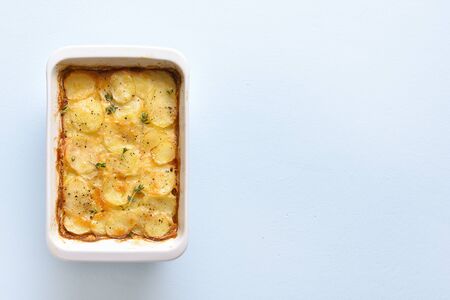Potato gratin in baking dish over blue stone background with free text space. Top view, flat layの写真素材