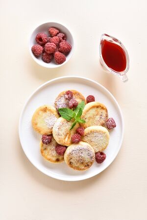 Healthy diet cottage cheese pancakes with fresh raspberries on plate over light stone background. Top view, flat layの写真素材