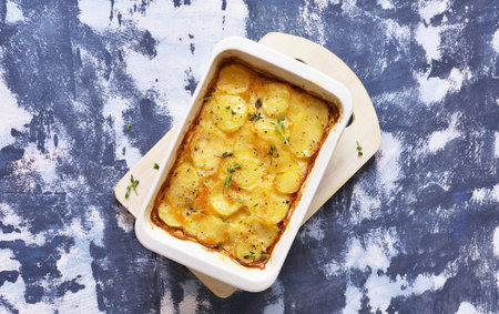 Potato gratin in baking dish over stone background. Top view, flat lay
