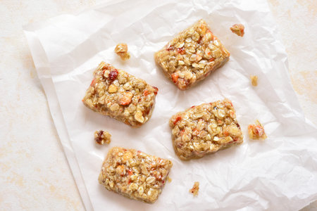 Honey no baked granola bar on paper over light stone background. Natural healthy snack. Top view,...
