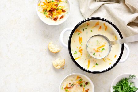 Delicious potato soup with bacon and cheddar cheese in bowl on light stone background with free space for text. Healthy diet dish for dinner. Top view, flat layの写真素材
