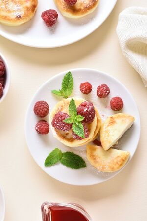 Cottage cheese pancakes with fresh raspberries on plate over light stone background. Top view, flat layの写真素材