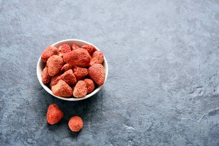 Dried strawberries in white bowl over blue stone background with free text space. Dehydrated strawberries. の写真素材