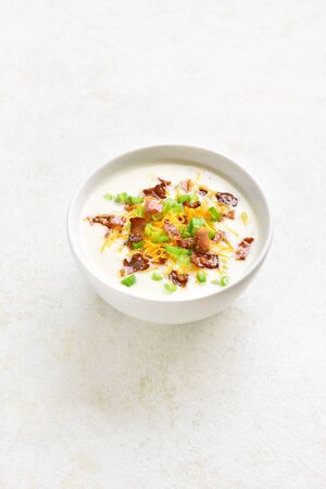 Creamy potato soup with bacon and cheddar cheese in bowl on light stone background with free space. Healthy diet dish for dinner.の写真素材