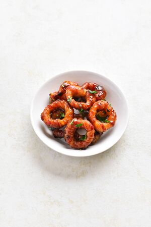 Bacon wrapped onion rings in bowl over light stone background with free space. の写真素材