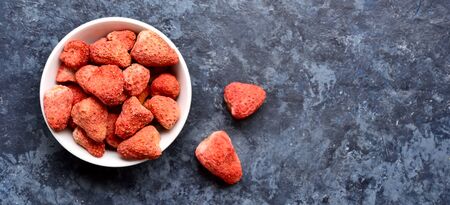 Dried strawberries in white bowl over blue stone background with free space for text. Dehydrated strawberries. Top view, flat layの写真素材