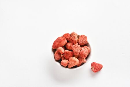 Dried strawberries in bowl over white stone background with free text space. Dehydrated strawberries. の写真素材