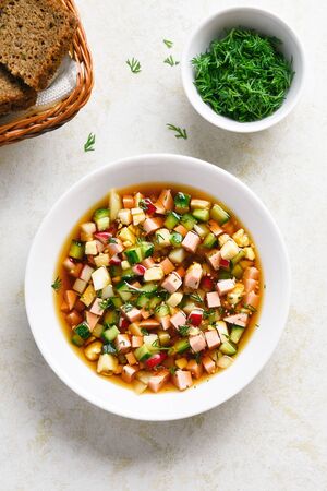 Cold russian Okroshka soup with sausage, vegetables and kvass over light stone background. Top view, flat layの写真素材