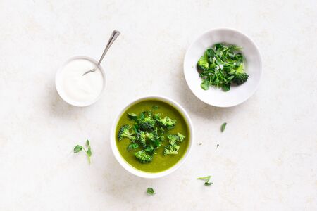 Healthy broccoli green pea cream soup in bowl over light stone background. Diet detox food concept. Top view, flat layの写真素材