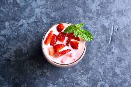 Strawberry yogurt with fresh berries in glass on blue stone background with free text space. Healthy food and drink concept. Top view, flat layの写真素材