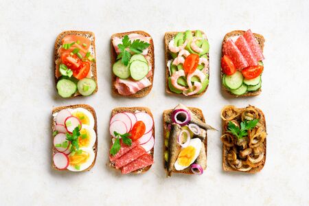 Set of different sandwiches with meat, vegetables, seafod. Assortment open sandwiches on light stone background. Tasty healthy snack. Top view, flat lay.の写真素材