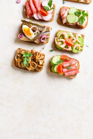 Set of different sandwiches with meat, vegetables, seafod. Assortment open sandwiches on light stone background with free text space. Tasty healthy snack. Top view, flat lay.の写真素材