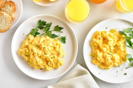Scrambled eggs on plates over white stone background. Top view, flat layの写真素材