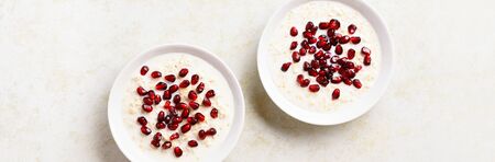 Pomegranate oats porridge in bowl over light stone background with free text space. Tasty healthy diet food for breakfast or lunch. Top view, flat layの写真素材