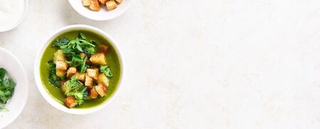 Healthy broccoli green pea cream soup with croutons in bowl over light stone background with free text space. Diet detox food concept. Top view, flat layの写真素材