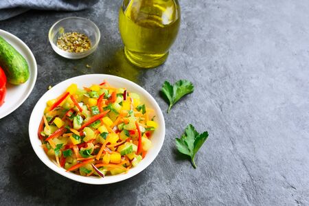 Healthy vegetable salad from bell pepper, cucumber, carrot, celery, greens in bowl over blue stone background with free text space. Organic natural or vegetarian vegan food concept.の写真素材