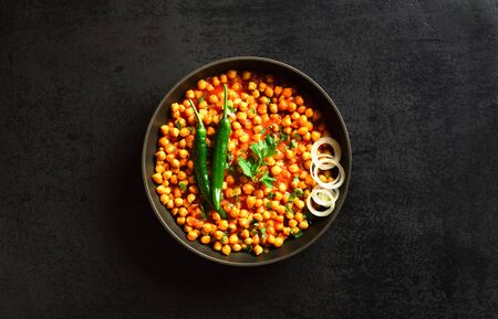 Crispy roasted chickpeas. Indian style dish over black stone background with free text space. Vegetarian vegan food concept. Top view, flat layの写真素材