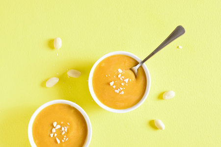 Peanut sauce in bowl over yellow background. Top view, flat lay