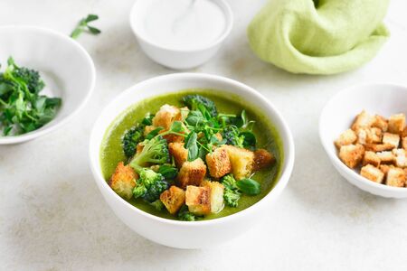 Healthy broccoli green pea cream soup with croutons in bowl over light stone background. Diet detox food concept.の写真素材